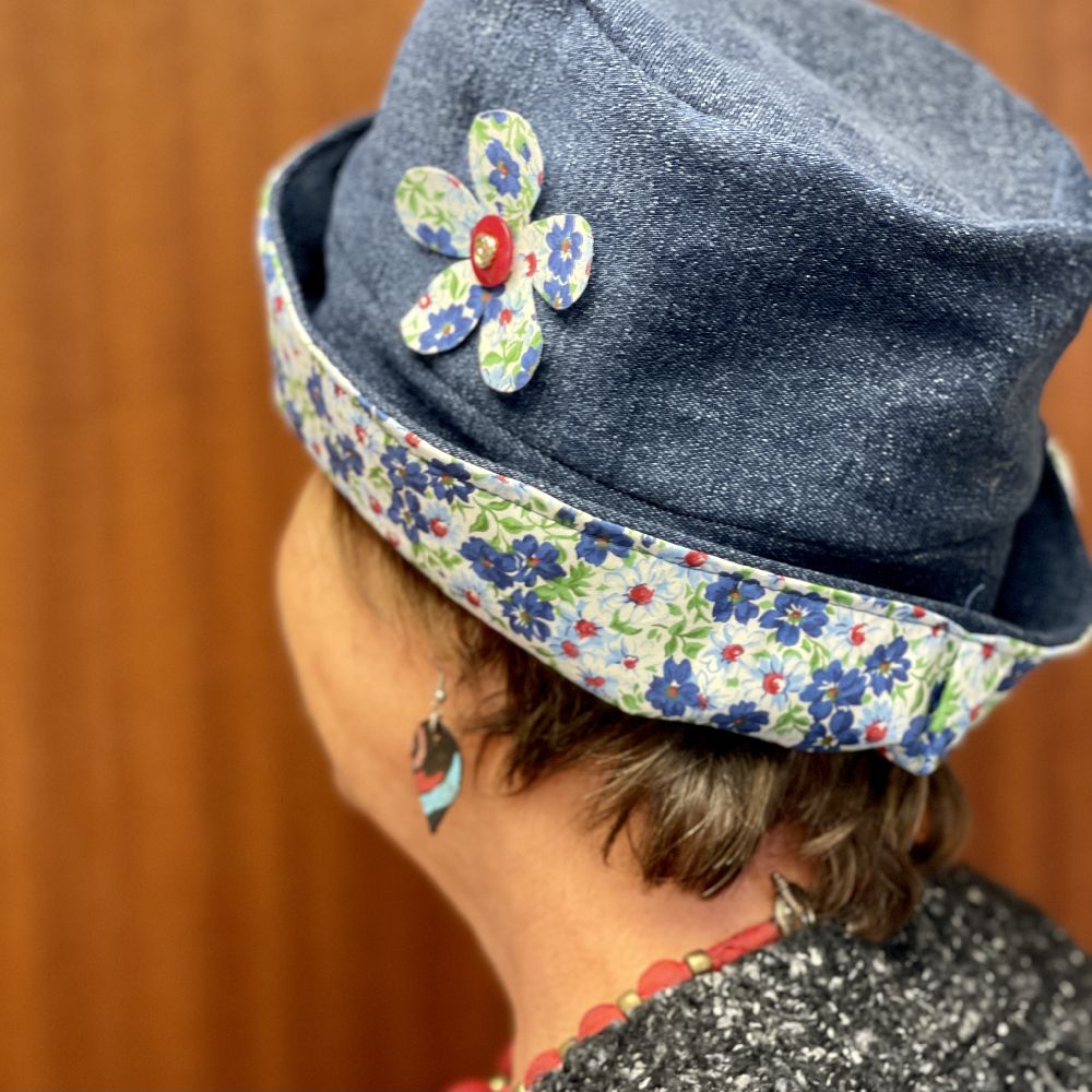 Photo of a woman modeling a hat made from recycled jeans, with an applique flower and matching lining