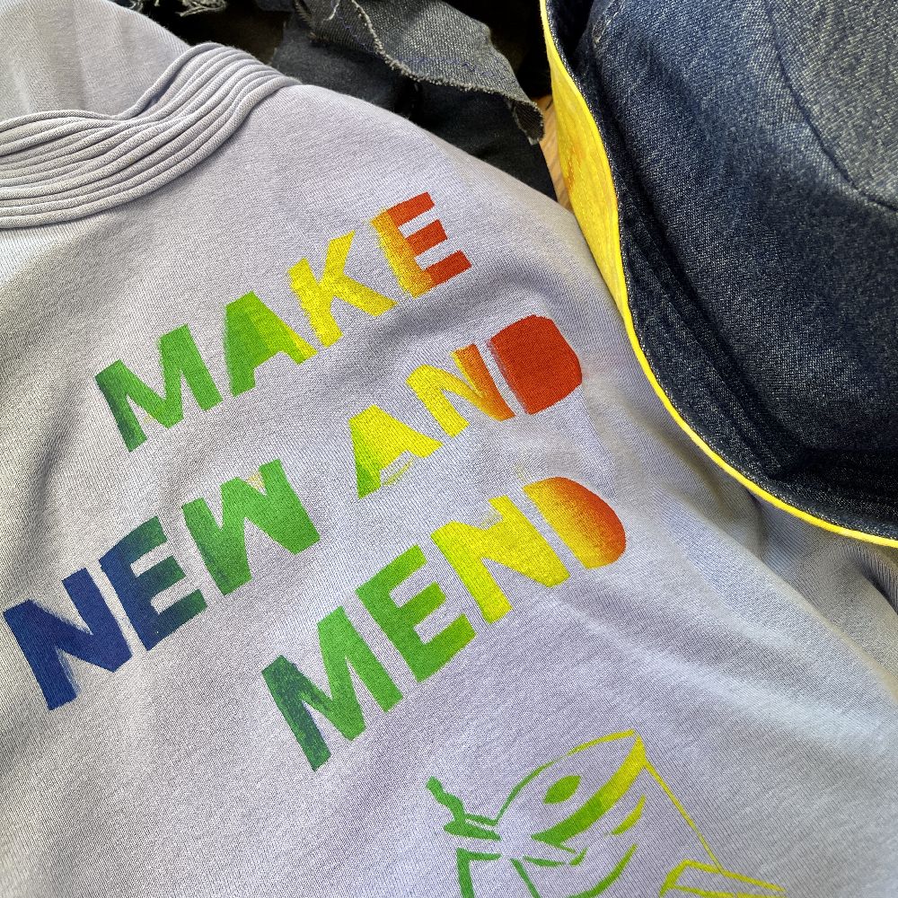 Close up photo of a recycled t-shirt with 'Make New And Mend' printed on in rainbow colours